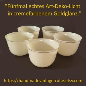 Puede incluir: Un juego de cinco cuencos de color crema con un borde dorado fino. El texto "Fünfmal echtes Art-Deko-Licht in cremefarbenem Goldglanz." aparece sobre los cuencos y la URL "https://handmadevintagetruhe.etsy.com" se encuentra en la parte inferior.