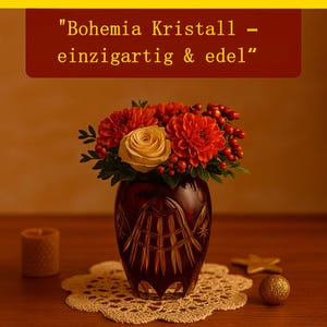 Può includere: Un vaso di cristallo rosso scuro con un bouquet di dalie arancioni, una rosa gialla e bacche rosse. Il vaso è appoggiato su un centrino color crema. Il testo sopra recita "Bohemia Kristall - einzigartig & edel".