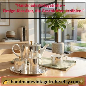 Op de afbeelding: Een zilveren theeset met een theepot, suikerpot, melkkan en kopje op een zilveren dienblad. De set heeft een textuurontwerp en staat op een houten tafel. De tekst "HandmadeVintagetrue - Design-Klassiker, die Geschichten erzählen." is zichtbaar.