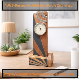 Può includere: Un orologio da scrivania in legno con un quadrante rotondo. L'orologio ha un corpo rettangolare in legno con accenti grigi e argentati. Il testo "W/B-Design: Architektur, die die Zeit misst." è in alto. L'URL del negozio Etsy è in basso.