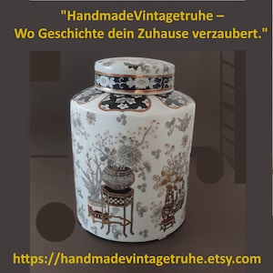 Può includere: Un vaso di ceramica bianco con coperchio, con disegni floreali e botanici neri e dorati. Il vaso ha una forma rotonda ed è decorato con motivi intricati. Il coperchio è anch'esso decorato con un motivo floreale in bianco e nero. Il testo in alto recita "HandmadeVintagetruhe - Wo Geschichte dein Zuhause verzaubert."