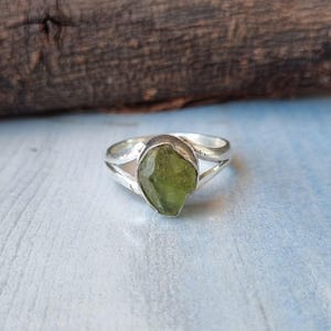 May include: A silver ring with a green gemstone set in a twisted band.