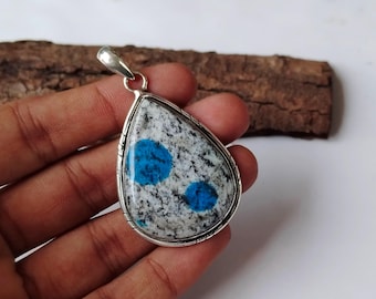 Könnte beinhalten: Ein silberner Anhänger mit einem tropfenförmigen blauen und weißen Stein. Der Stein hat ein gesprenkeltes Muster mit blauen Flecken.