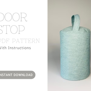 May include: A cylindrical, light blue door stop with a fabric loop handle. The text "DOOR STOP PDF PATTERN With Instructions" is printed on the left side, with an "INSTANT DOWNLOAD" button below.