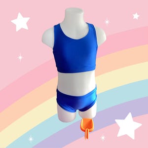 May include: A blue swimsuit with a tank top and high-waisted bottoms. The swimsuit is on a white mannequin against a pink and rainbow background.