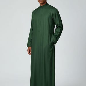 May include: A dark green, long-sleeved kurta with a mandarin collar. The garment has a relaxed fit and pockets. The text "CUSTOM KURTAS" is displayed at the bottom left of the image.