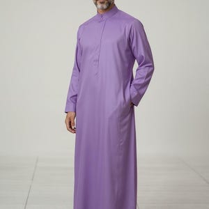 May include: A long, lavender kurta with a mandarin collar and long sleeves. The garment has a front placket and side pockets. The text "CUSTOM KURTAS" is visible in the lower left corner.