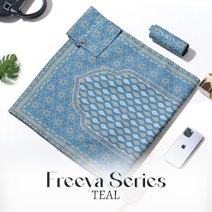 Op de afbeelding: Teal gebedskleed met een geometrisch patroon en bladontwerp. De mat maakt deel uit van de Freeva-serie en bevat een bijpassende draagtas. De tekst "Freeva Series TEAL" wordt onderaan de afbeelding weergegeven.