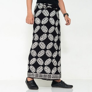 Peut inclure: Sarong à motifs noirs et blancs avec une bordure blanche. Le sarong est enroulé autour de la taille d'une personne et noué sur le côté.