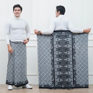Peut inclure: Un paréo long portefeuille présentant un motif géométrique gris et noir avec un panneau central vertical orné de motifs floraux complexes. Le tissu affiche un motif en grille de losanges répétitif et une bordure décorative foncée.