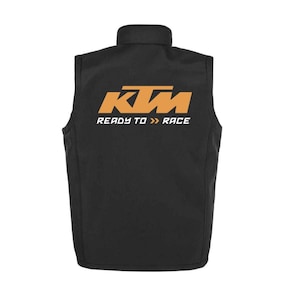 May include: Black vest with a stand-up collar. The back of the vest features the KTM logo in orange and white, with the text "READY TO RACE" below it. The vest is sleeveless and appears to be made of a soft, durable material.