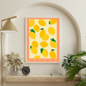 May include: A printable art print with a peach background and white frame featuring a pattern of yellow lemons with green leaves. The text "LEMONS" is printed in white at the bottom of the print.