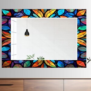 Peut inclure: Un miroir rectangulaire avec une bordure en vitrail color&eacute; pr&eacute;sentant un motif g&eacute;om&eacute;trique de feuilles dans des tons de bleu, vert, orange et jaune.