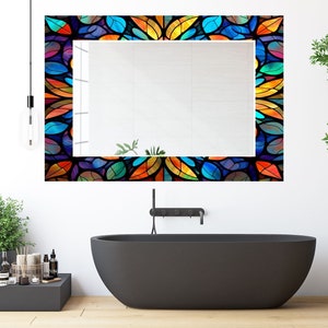 Peut inclure: Un miroir de salle de bain avec un cadre en vitrail color&eacute; repr&eacute;sentant un motif de feuilles dans des tons de bleu, vert, orange, jaune et rouge.