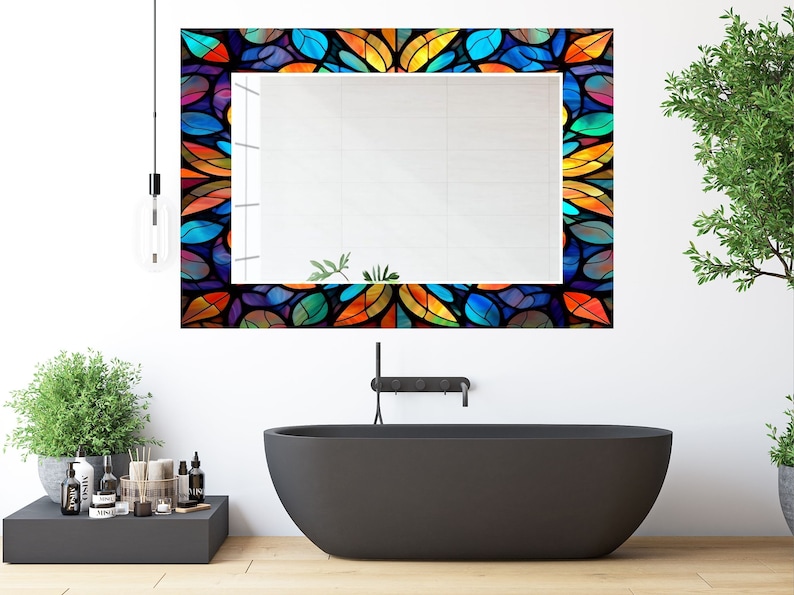 Peut inclure: Un miroir de salle de bain avec un cadre en vitrail color&eacute; repr&eacute;sentant un motif de feuilles dans des tons de bleu, vert, orange, jaune et rouge.