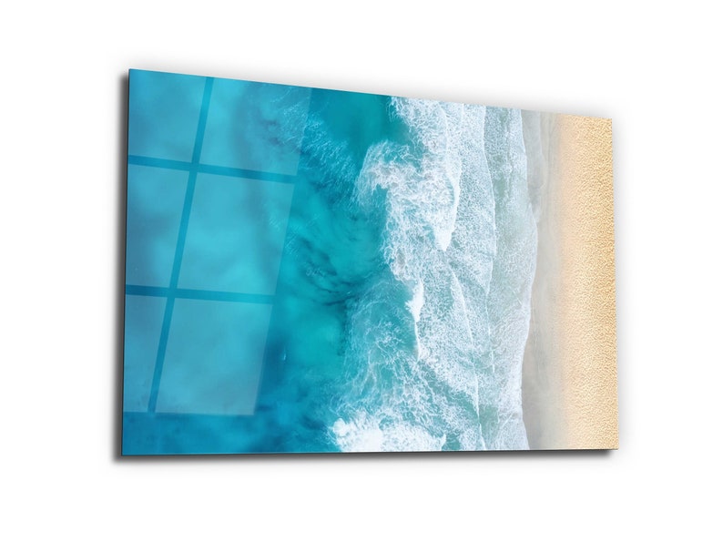 May include: An aerial view of a sandy beach with turquoise blue ocean waves crashing on the shore.