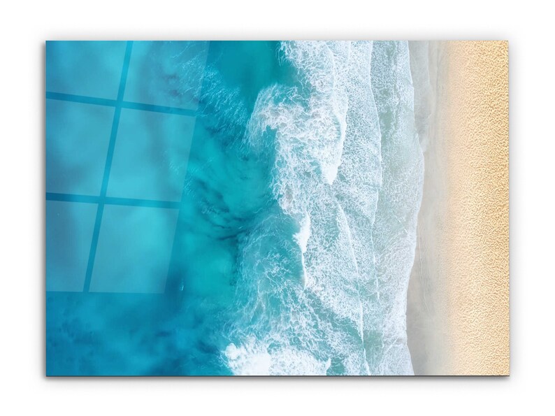 May include: An aerial view of a sandy beach with turquoise blue ocean water and white foamy waves crashing on the shore.