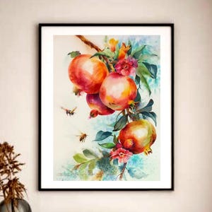 Pode incluir: Uma pintura em aquarela emoldurada de romãs em um galho, com frutos vermelhos e laranjas, folhas verdes e pequenas flores vermelhas. A obra de arte está em uma moldura preta, exibida em uma sala bem iluminada.