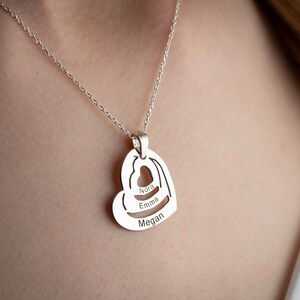 Può includere: Collana d'argento con un ciondolo a forma di cuore con i nomi "Nora", "Emma" e "Megan" incisi all'interno.