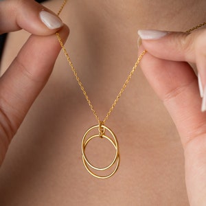 May include: A gold chain necklace with a pendant featuring two interlocking circles.