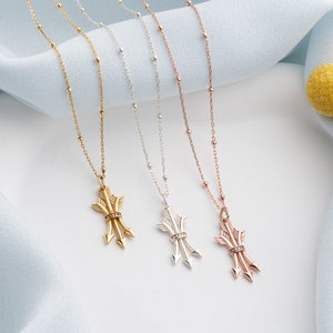 May include: Three gold, silver, and rose gold necklaces with arrowhead pendants. Each necklace features a delicate chain with small beads.