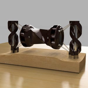 Puede incluir: Un objeto de color marrón oscuro en forma de hélice con un diseño retorcido, suspendido entre dos soportes en espiral negros sobre una base de madera.