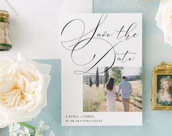 以下が含まれることがあります： 白い背景と黒い書道で書かれた「Save the Date」カード。カードには、花畑を歩くカップルの写真が載っています。カードのテキストには、「Save the Date」と「Laura & Chris、07.08.24、ナパバレー」と書いてあります。
