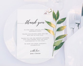 以下が含まれることがあります： 白い紙に黒い文字で書かれたサンキューカード。カードには、結婚式の祝賀会への出席とサポートに対する感謝の気持ちを込めたメッセージが書かれており、「ありがとう」と「愛を込めて、ジェナ＆クリスチャン」と署名されています。