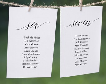 May include: Two white cards with black text hanging from a string with clothespins. The cards are labeled "six" and "seven" and list names for a wedding reception seating chart.
