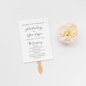 May include: A white wedding programme fan with black text. The text reads "Welcome to the wedding of Julia Rawlings and Steven Wagner June 30, 2022 | Houston, Texas The Ceremony Prelude Seating of the Family Processional Welcome & Introduction Readings Exchange of Vows & Rings Pronounce of Marriage Recessional"
