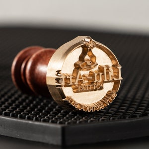 May include: A brass stamp with a wooden handle. The stamp features a logo with the text "LILA-ART POTTERY SLOV. BISTRICA SLO."