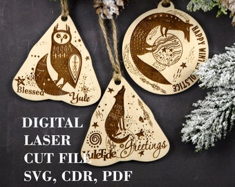May include: Three laser-cut wooden ornaments with a winter solstice theme. The ornaments feature a crescent moon with an owl, a fox, and a wolf. The text on the ornaments reads "Blessed Yule", "Happy Winter Solstice", and "Yuletide Greetings".