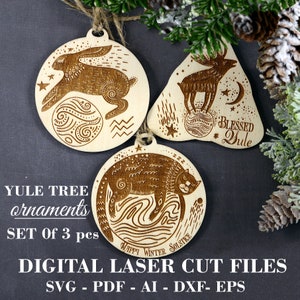 May include: Set of three laser cut wooden ornaments featuring a rabbit, a deer, and a cat. Each ornament has a unique design with a celestial theme and text that reads "Blessed Yule" and "Happy Winter Solstice".