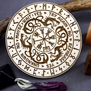 May include: A wooden circular divination board with a compass in the center and two dragons surrounding it. The board is inscribed with runes and the words "Maybe Wait Yes Try Again No Rephrase Yes Unknown".