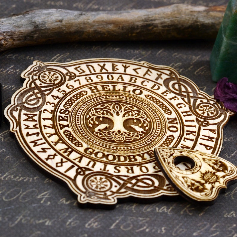 K&ouml;nnte beinhalten: Holz-Ouija-Brett mit einem Lebensbaum-Design, Zahlen, Buchstaben und den W&ouml;rtern "Hallo" und "Auf Wiedersehen". Ein Holz-Planchette ist enthalten.