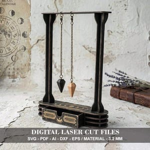 May include: A dark brown wooden pendulum stand with two hanging pendulums. One pendulum is black, the other is natural wood. The stand has a drawer with gold accents and the text "DIGITAL LASER CUT FILES".