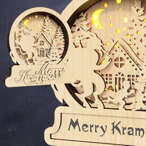 May include: A wooden Christmas ornament with a cut-out design of a reindeer pulling a sleigh with a house and a Christmas tree. The ornament has a light brown finish and features the text "Merry Krampus".