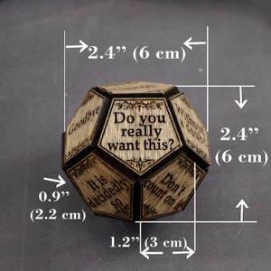 K&ouml;nnte beinhalten: Ein mehrseitiger Holzw&uuml;rfel mit verschiedenen Spr&uuml;chen, die auf jede Seite eingraviert sind. Der W&uuml;rfel hat einen Durchmesser von 6 cm. Die Spr&uuml;che lauten: "Do you really want this?", "It is decided so", "Goodbye", "Without a doubt", "Don't count on it".
