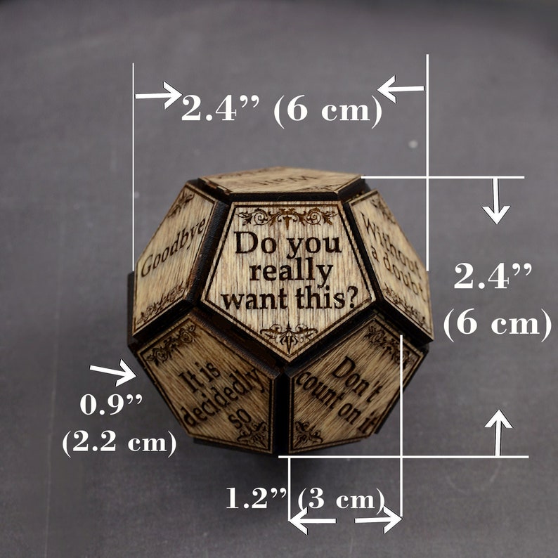K&ouml;nnte beinhalten: Ein mehrseitiger Holzw&uuml;rfel mit verschiedenen Spr&uuml;chen, die auf jede Seite eingraviert sind. Der W&uuml;rfel hat einen Durchmesser von 6 cm. Die Spr&uuml;che lauten: "Do you really want this?", "It is decided so", "Goodbye", "Without a doubt", "Don't count on it".