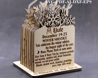 May include: A laser cut wooden Yule wheel with a snowflake design. The wheel is decorated with the text "Yule December 19-23 Winter Solstice" and includes information about the celebration of the winter solstice. The text also includes "Moon Phase: Dark or new moon" and "Altar Items & Decor: Yule log, evergreen garlands and wreaths, mistletoe ball, winter botanicals, wassail, reá and green candles". The text also includes "Rituals: shadow work, cleansing, grounding, peace, hope, solar magic". The wheel is made of 3mm, 3.2 (1/8 in), and 4mm wood.