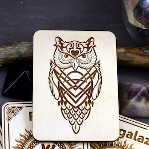 May include: A wooden plaque with a laser-etched design of an owl with intricate Celtic knotwork. The owl's eyes are detailed and the design is in shades of brown.
