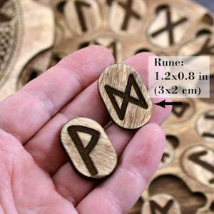 Puede incluir: Dos runas de madera, una con el s&iacute;mbolo "P" y la otra con el s&iacute;mbolo "M", se sostienen en una mano. Las runas miden 1,2 x 0,8 pulgadas (3 x 2 cm).