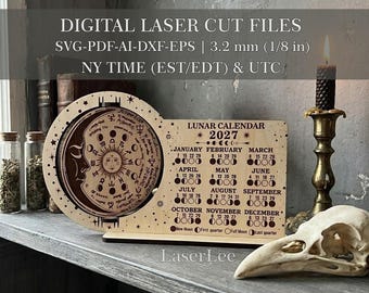 May include: A light-coloured wooden 2027 lunar calendar with a circular zodiac design featuring a sun and moon face, alongside a rectangular grid of months and moon phases. The text reads DIGITAL LASER CUT FILES, 3.2 mm (1/8 in), and LaserLee.