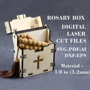 May include: A wooden box with a cross design and a tassel. The box is open and contains a wooden rosary. The box is made from 1/8 inch (3.2mm) thick wood. The text "ROSARY BOX DIGITAL LASER CUT FILES SVG-PDF-AI DXF-EPS Material - 1/8 in (3.2mm)" is printed on the image.