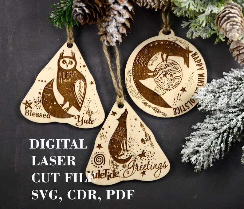 May include: Three laser-cut wooden ornaments with a winter solstice theme. The ornaments feature a crescent moon with an owl, a fox, and a wolf. The text on the ornaments reads "Blessed Yule", "Happy Winter Solstice", and "Yuletide Greetings".