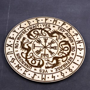 May include: A wooden circular board with a compass design in the center. The board is surrounded by a circle of text that reads "NOW MAYBE WAIT & YES TRY AGAIN NOW REPHRASE & UNKNOWN YES".