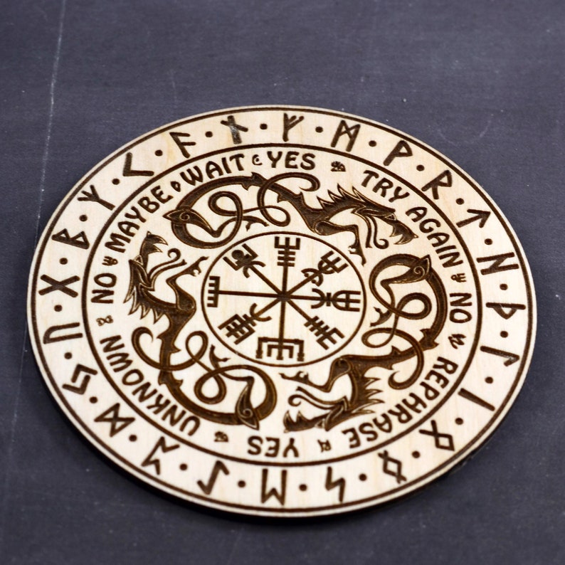 May include: A wooden circular board with a compass design in the center. The board is surrounded by a circle of text that reads "NOW MAYBE WAIT & YES TRY AGAIN NOW REPHRASE & UNKNOWN YES".