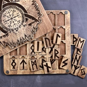 May include: Wooden game board with a carved design of a wolf and a compass. The board has slots for wooden tiles with runes carved on them. The runes are arranged in a line on the board.