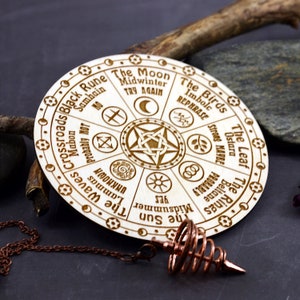 K&ouml;nnte beinhalten: Ein Holz-Divinationsbrett mit einem Pentagramm in der Mitte und acht Abschnitten, die mit den Namen keltischer Feiertage und zugeh&ouml;rigen Schl&uuml;sselw&ouml;rtern beschriftet sind. Das Brett wird mit einem Pendel verwendet, um F&uuml;hrung zu erhalten.