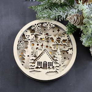 Pu&ograve; includere: Un ornamento natalizio in legno con un design a taglio di Santa Claus che vola su una slitta trainata da renne sopra un villaggio innevato. L'ornamento &egrave; illuminato da luci LED bianco caldo.